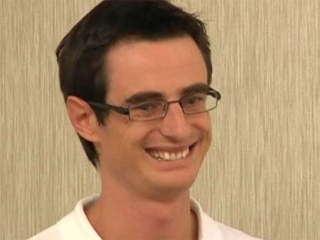 a man wearing glasses and smiling at the camera