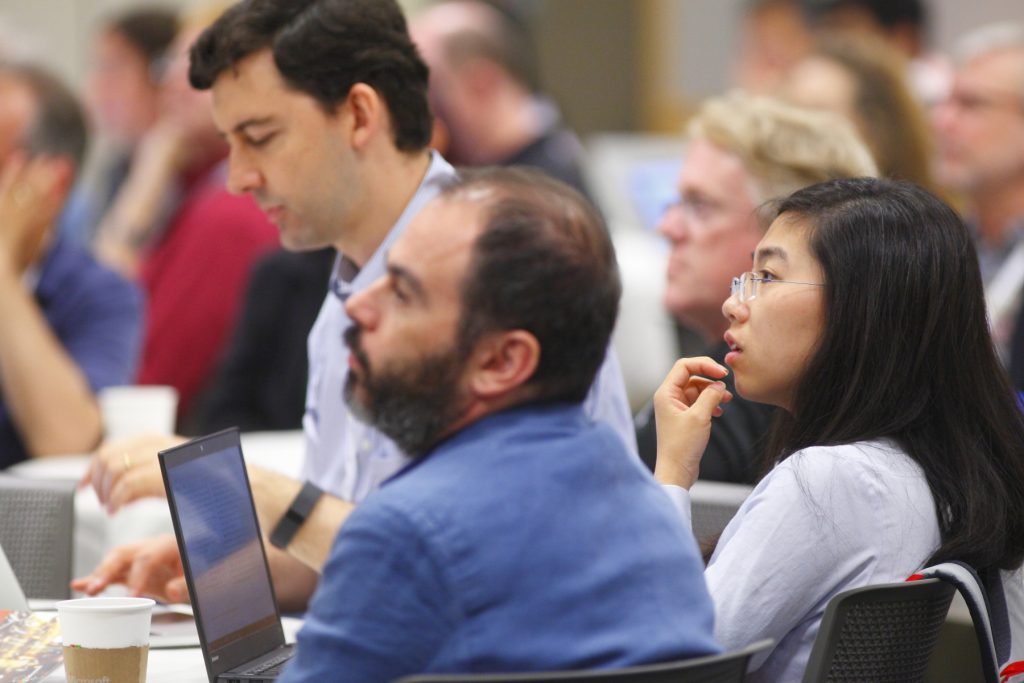 a group of people sitting at a table using a laptop