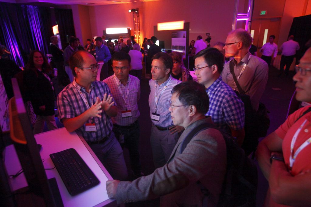 a group of people standing in front of a laptop