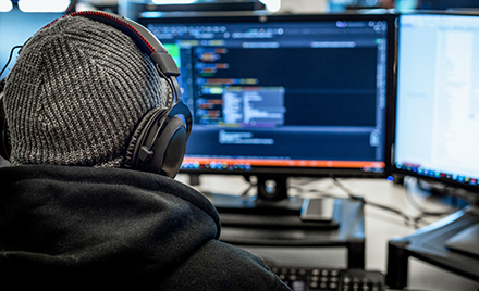 A tech worker using a PC workstation with headphones on.