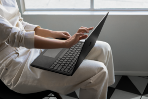 Contextual image of woman touching screen while working on Black Surface Laptop2.