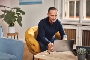 Adult male working from coffee table on Dell laptop.