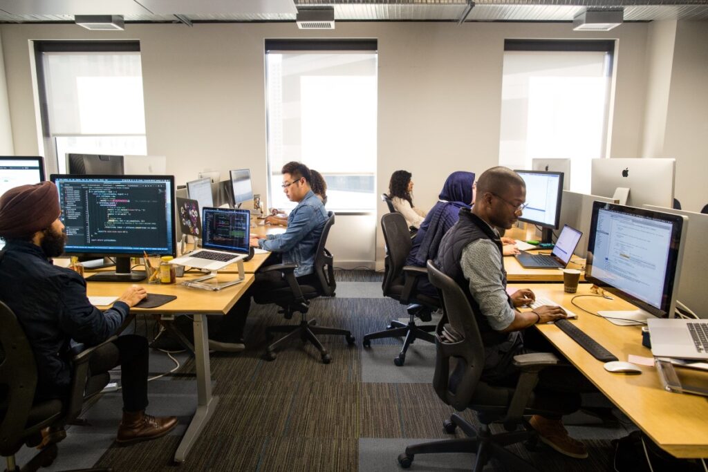 Female and male developers at at work; coding individually and sometimes collaboratively in an enterprise office space using Visual Studio for Mac.