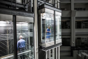 Photo of business woman and man in separate glass elevators.