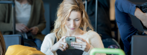 Image of a woman in an airport working on her phone.