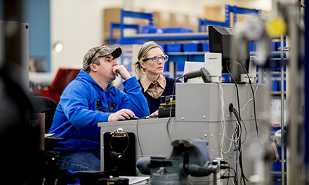 Image of two firstline workers looking at a computer monitor.