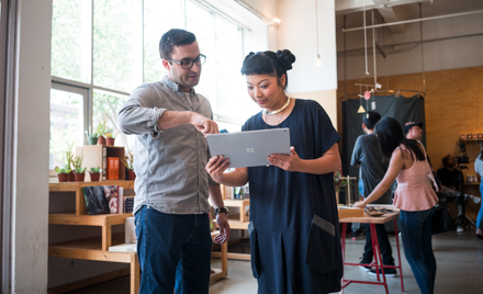 Image of two coworkers looking at a tablet.