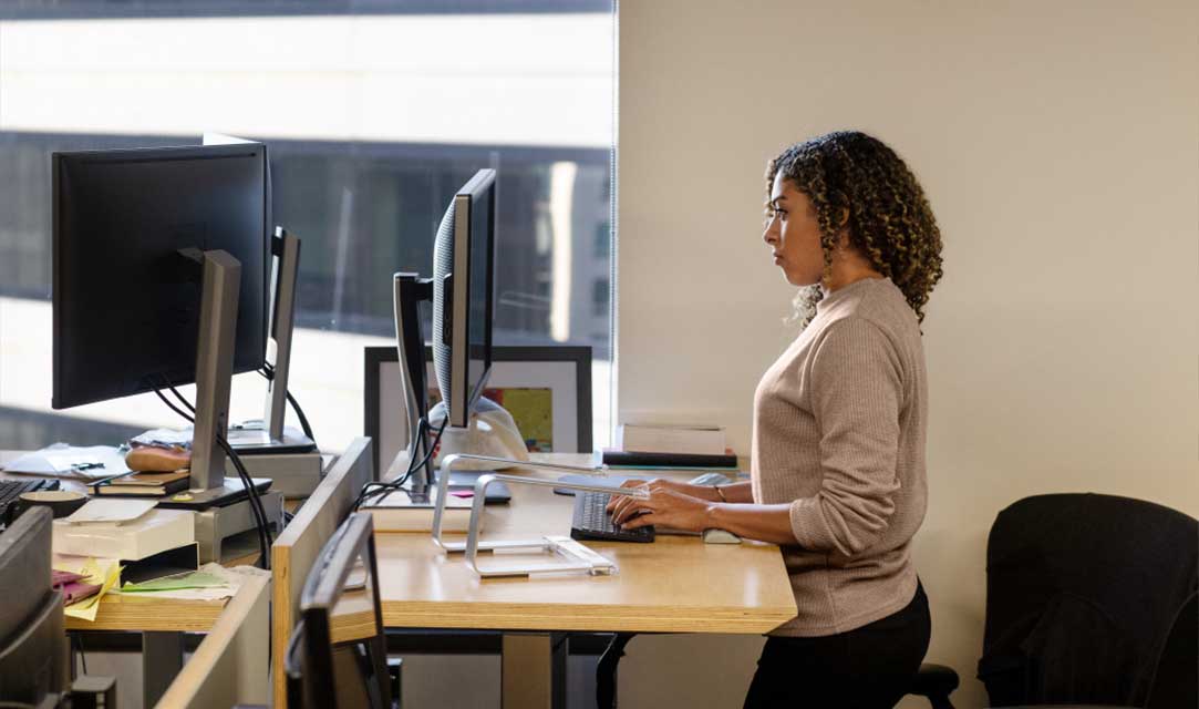 Black female developer doing focused work at a standing desk in enterprise workspace.
