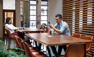 Image of two workers working at separate tables in a casual office environment.