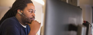 Image of a firstline worker looking at several computer monitors.