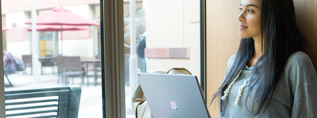 Image of a worker smiling out a window with her laptop open.