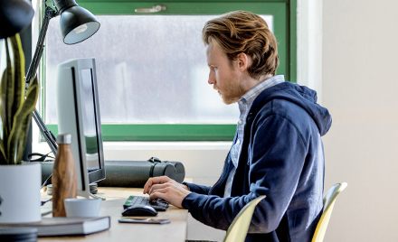 Image of a worker sitting at his desk, hands hovering over his keyboard.