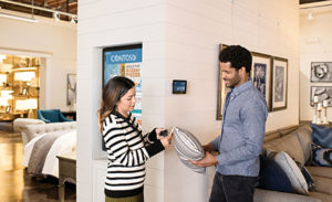 Two firstline workers examine a pillow in a shop.