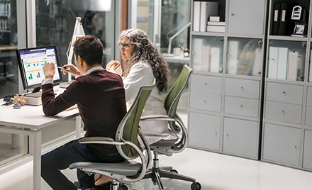 Image of two healthcare workers collaborating over a computer.