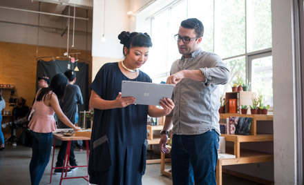 Image of two coworkers looking at a tablet.