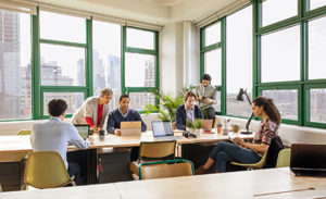 Image of a group of coworkers collaborating in a conference room, each on a variety of different devices.