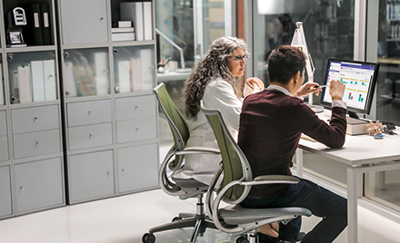 Image of two healthcare workers collaborating over a computer.