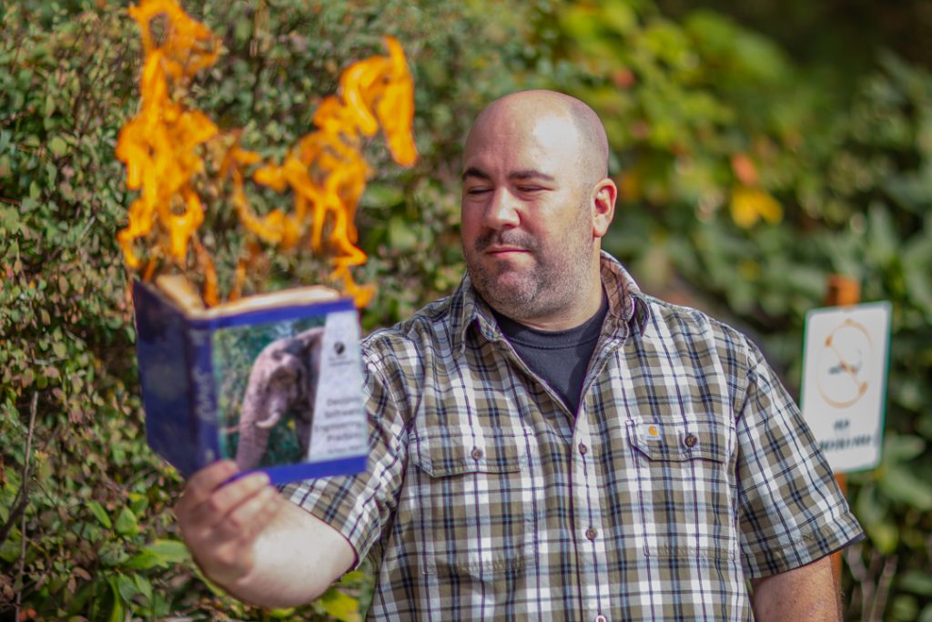 James is pictured outside burning a book on software engineering practices.