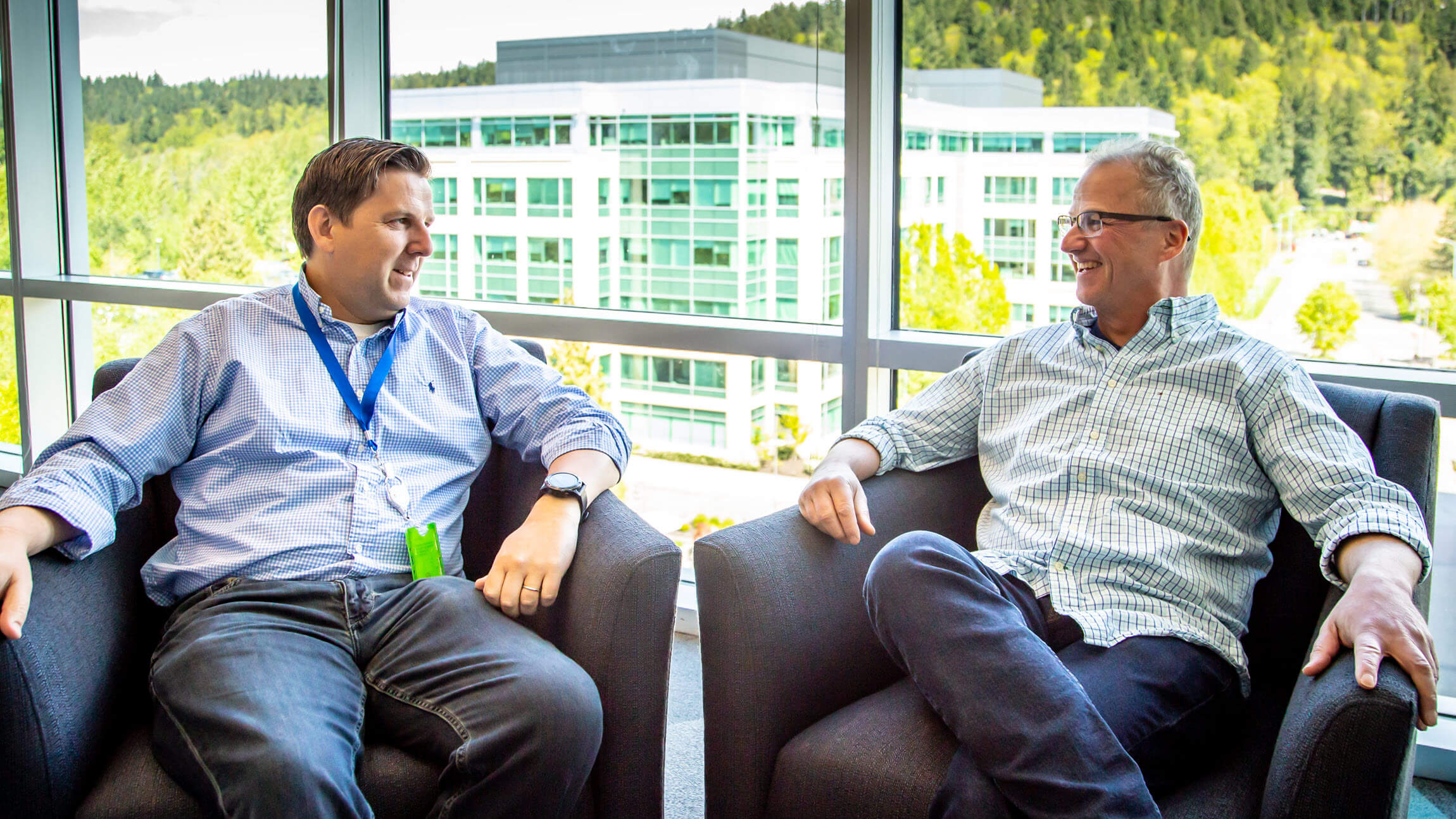 Enda Sullivan and Blake Barrow sit on a couch in a Microsoft common area talking to each other.