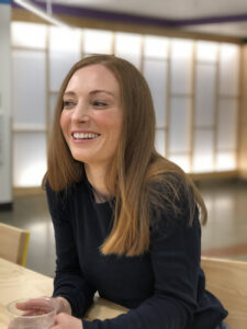 Eva Etchells smiles as she leans forward in her chair in a café on the Microsoft campus. 