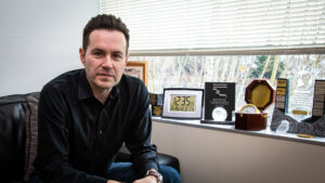 Ludo Hauduc leans forward from a seated position in his office and looks intently into the camera.