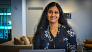 Vidya Iyer sits behind a Surface laptop. She is smiling.