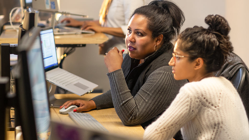 Two female developers collaborating in their enterprise office space.