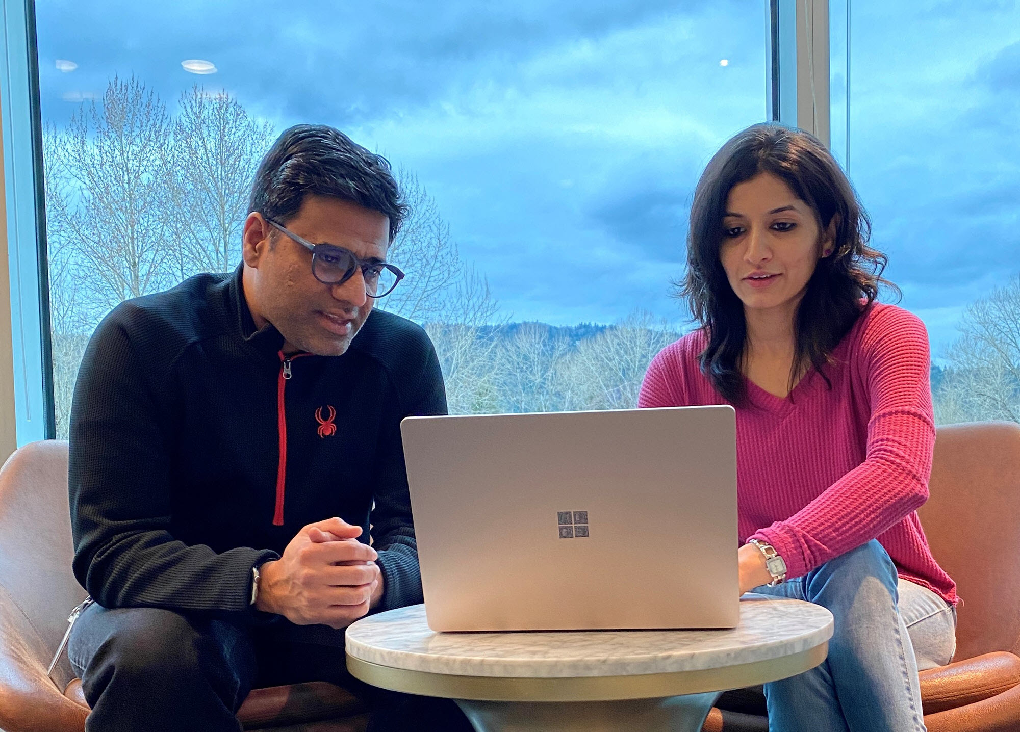 Microsoft CSEO colleagues Akshatha Pai and Iliyas Chawdhary sit together looking at a laptop.