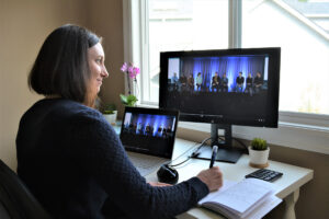 Kimberly Nafziger sits at her desk in her home office. The Ask Me Anything meeting that she’s managing is shown on her laptop and monitor.