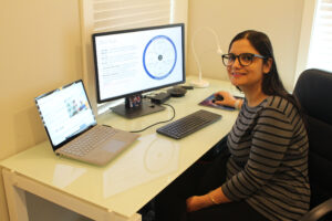 Darshana Pandya sits at her desk and smiles. Her computer monitor displays a slide that lists the elements of a Zero Trust security model.