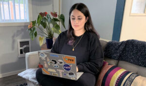 Al-Faham sits on the couch while on her laptop.