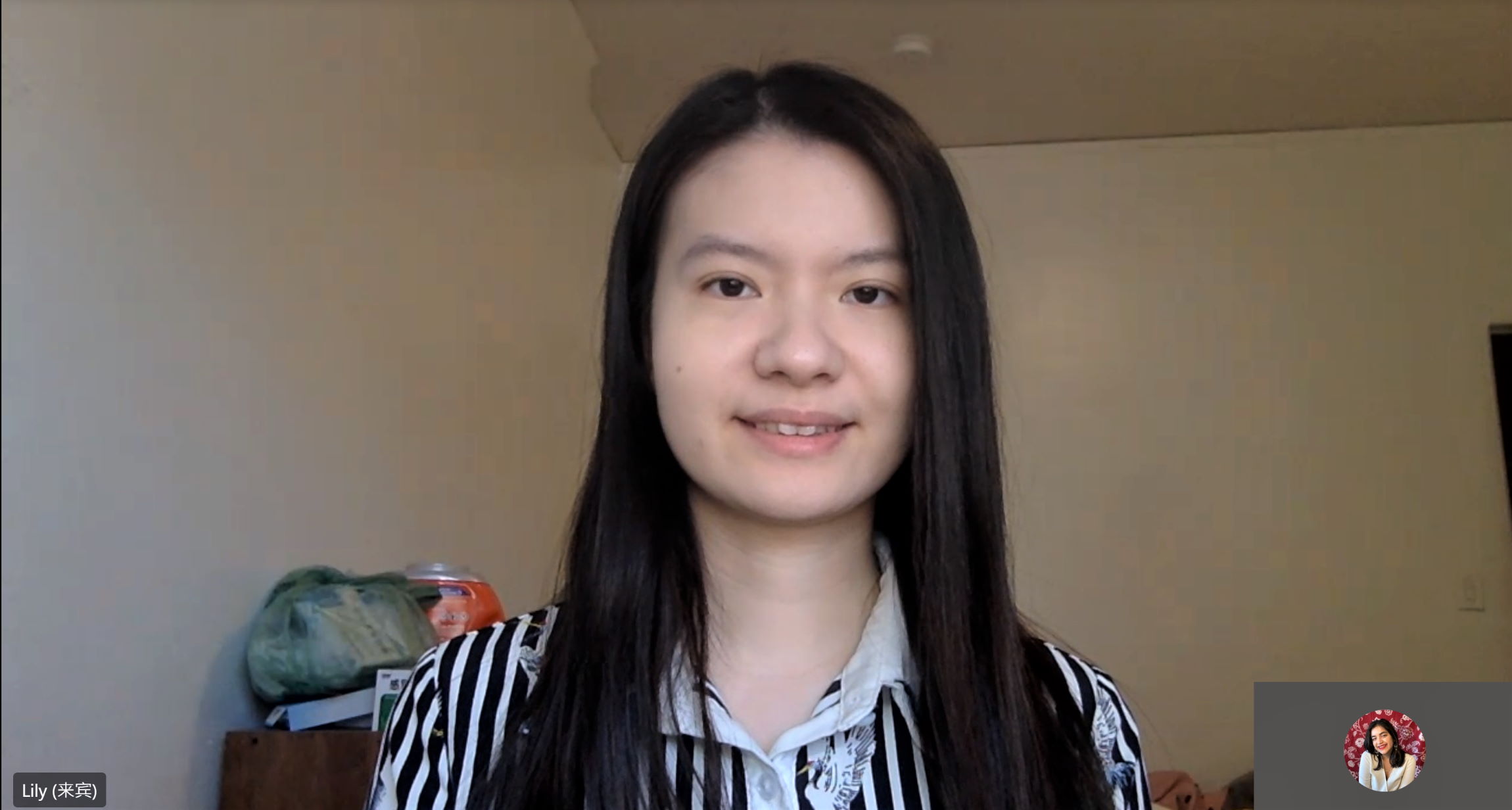 Lily Zhang looks at her camera during a Microsoft Teams meeting. She is pictured at her desk in her home.