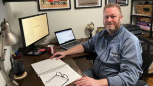 Dan Detjen smiles while working at a desk in his home office.