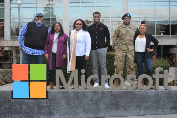 Dwight Jones and his family members stand next to a Microsoft sign on the Microsoft campus and look at the camera.