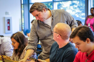 Robert Koester stands next to new employees helping them with their StepBar application.