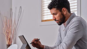 A Microsoft employee sits at his computer working in a home office.