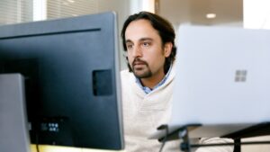 Male office worker looking at monitor on desk.