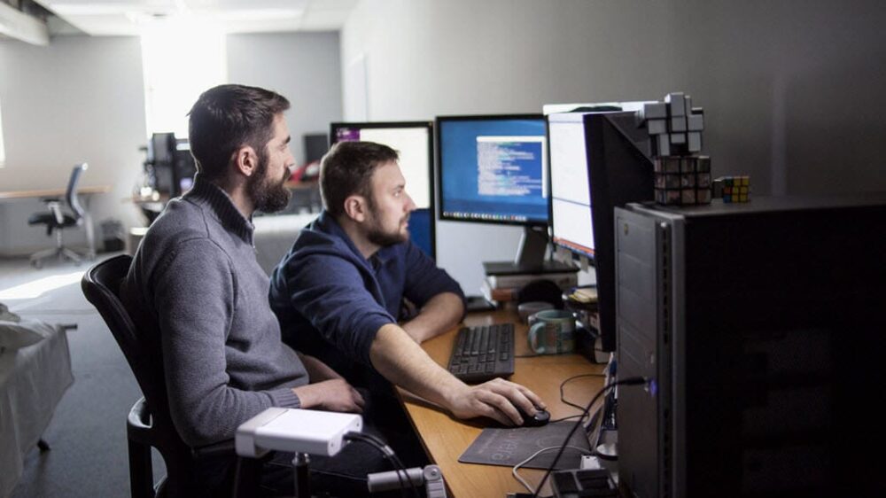 Two software developers sitting using a computer.