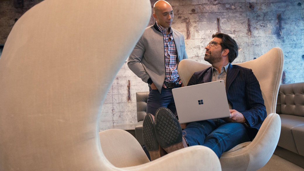 Businessmen in office building collaborating on laptop.