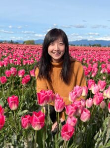 Han smiles as she kneels in a field of tulips.