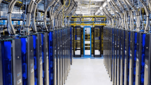 Rows of servers are shown on either side of a walkway in a datacenter.