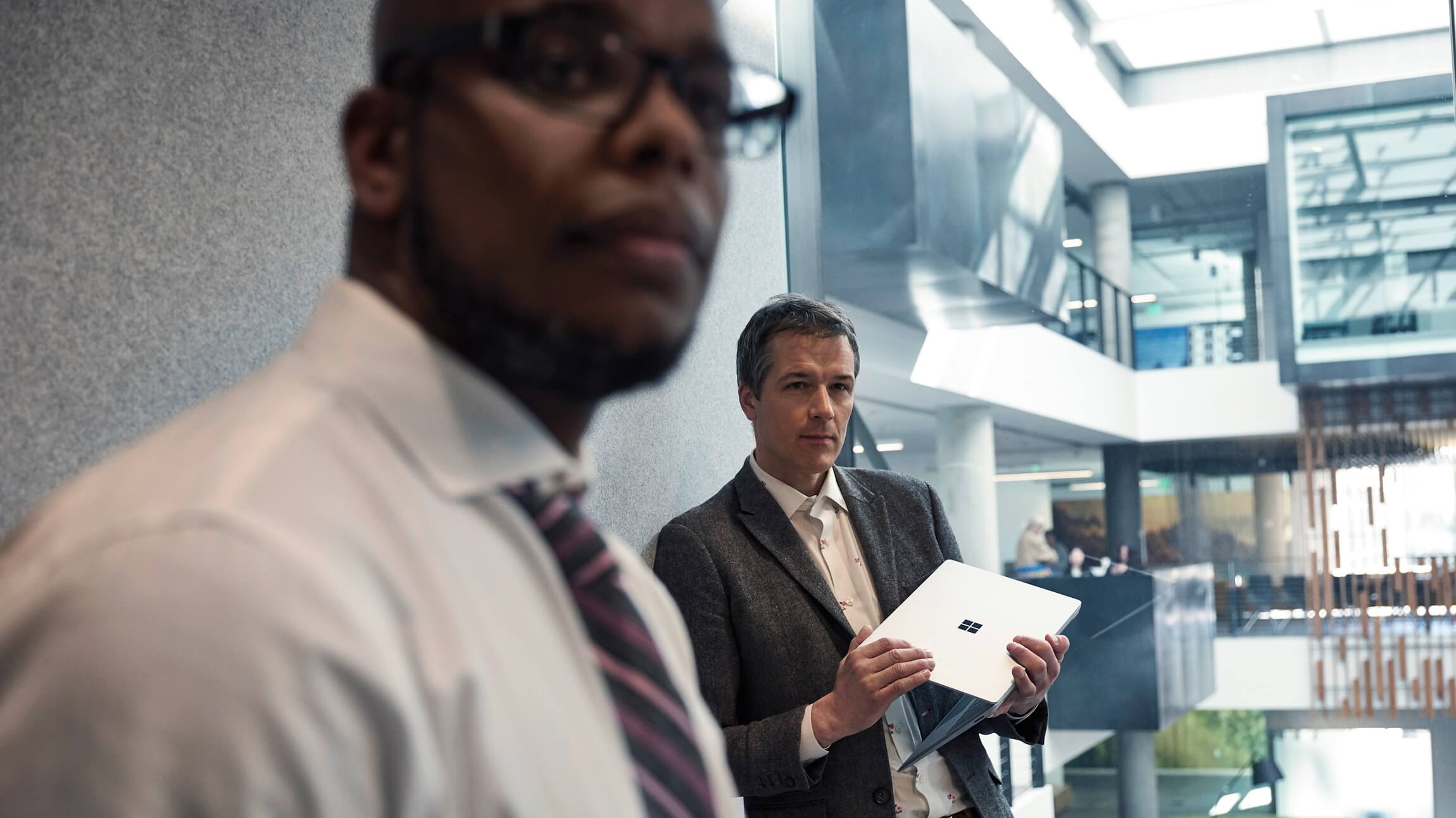 Two employees listen to a presentation in a Microsoft conference room.