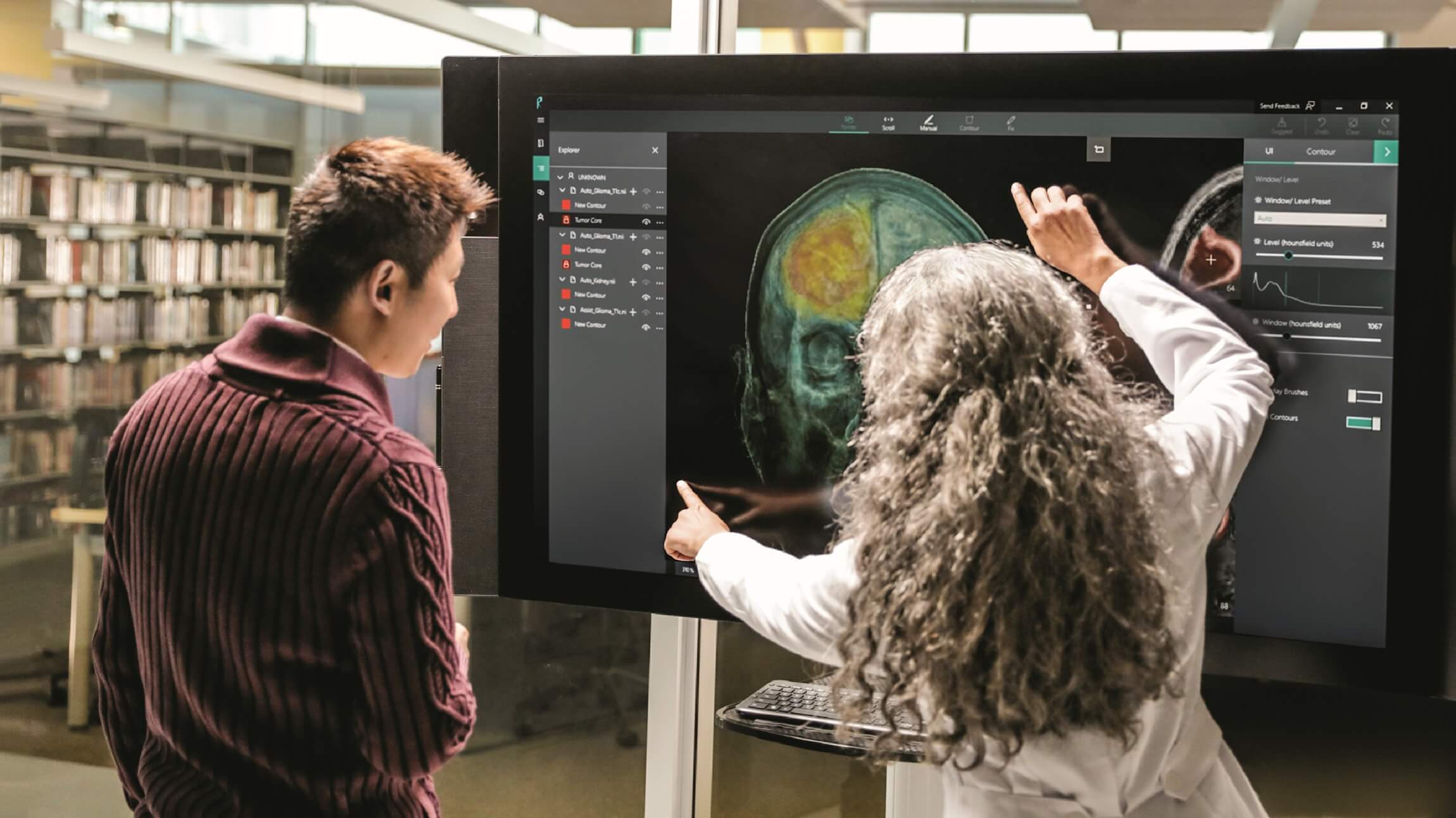 Two researchers view a large video screen with simulated healthcare information.