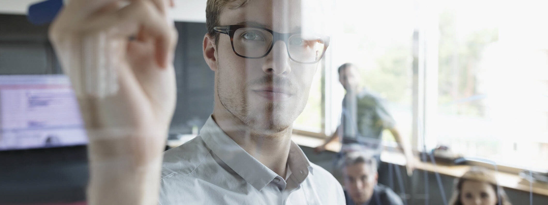 Man writes on transparent board.