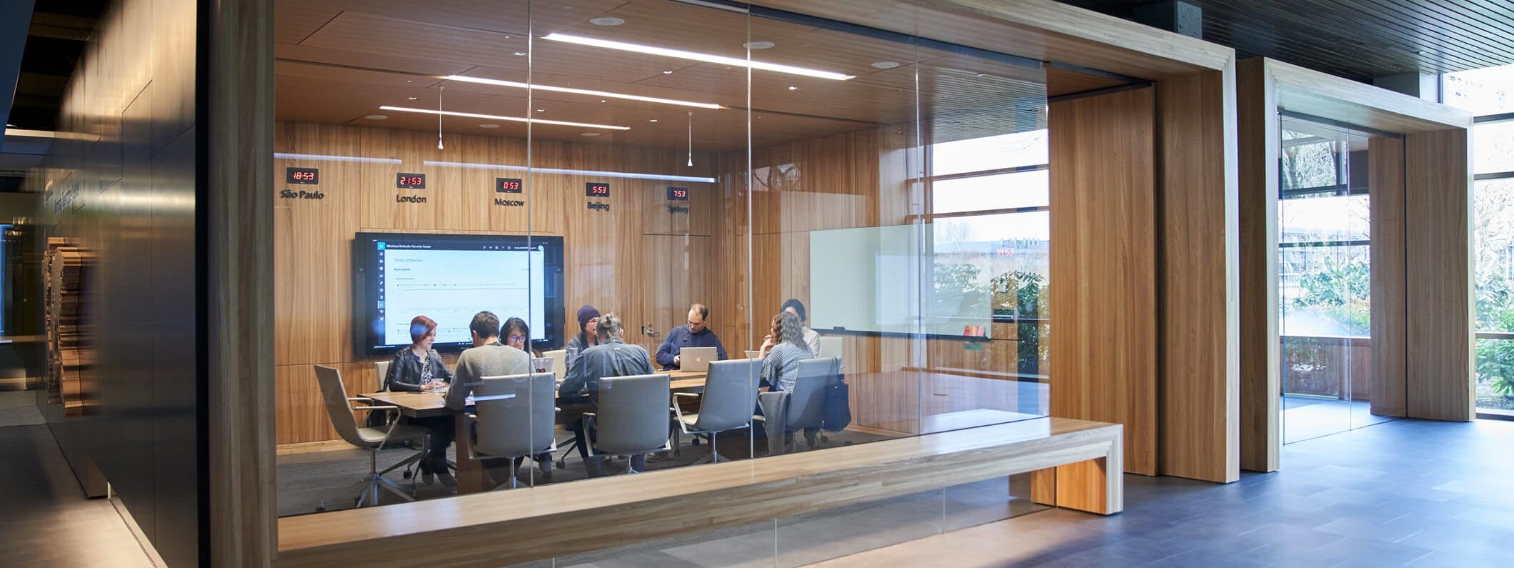 Outside of a conference room or board room meeting including people sitting around table in a room with international time clocks.