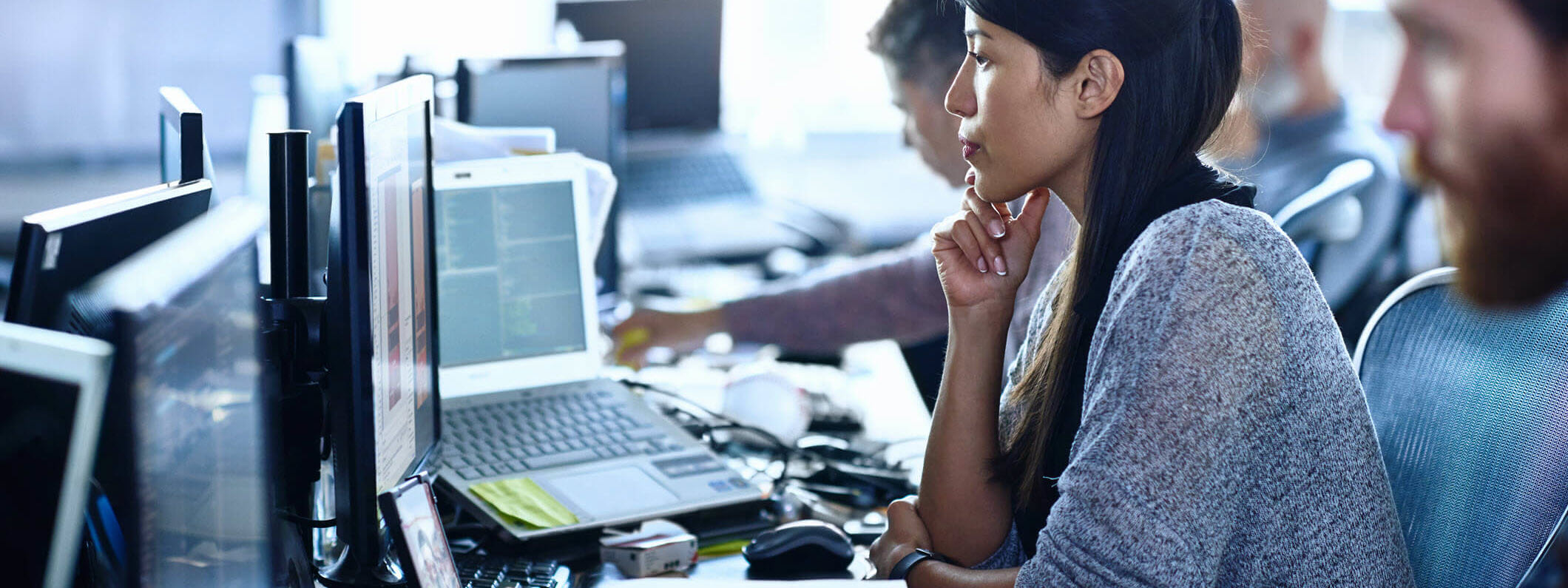 Woman in open office studies monitor.