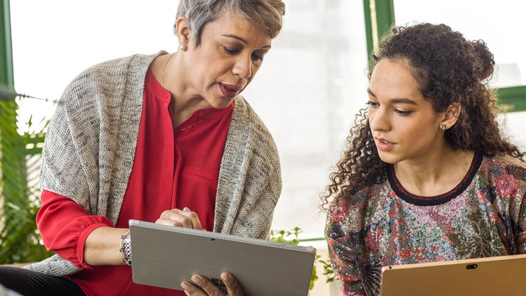 Two women are looking a the same laptop.