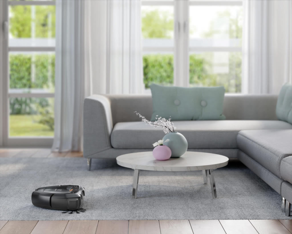 A Pure i9, a cloud-connected robot vacuum. cleans a rug and flooring while navigating a table and sofa