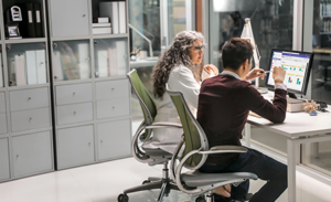 Image of two firstline workers collaborating at a desk in an office space.