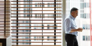 Image of a man in an office looking at his phone.